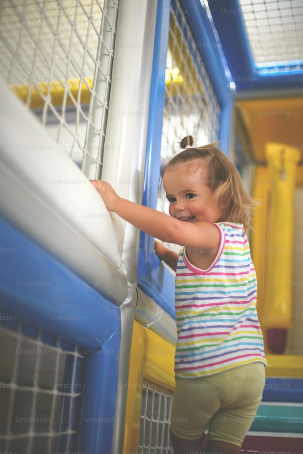 Little Caucasian baby in playground. Small girl climbs up the stairs