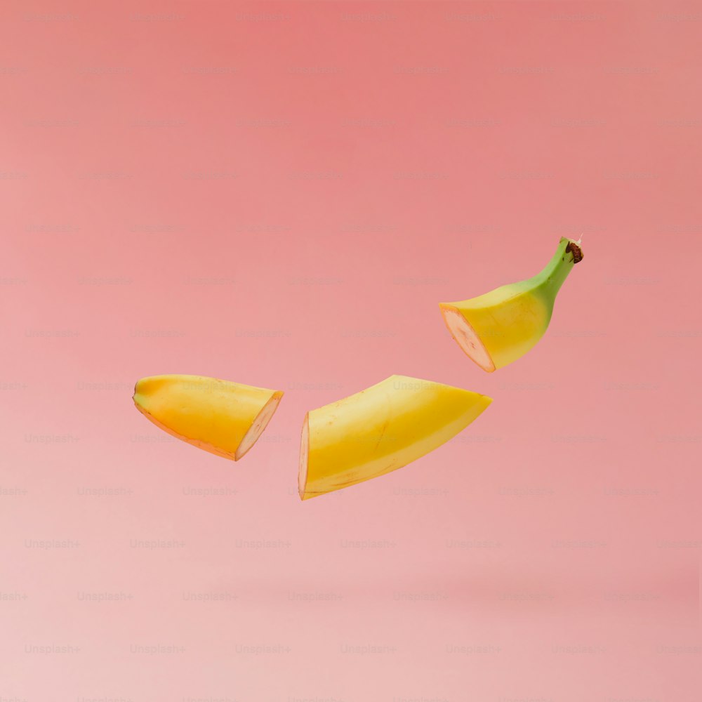 바나나는 파스텔 핑크 배경에 얇게 썬다. 최소한의 과일 개념.
