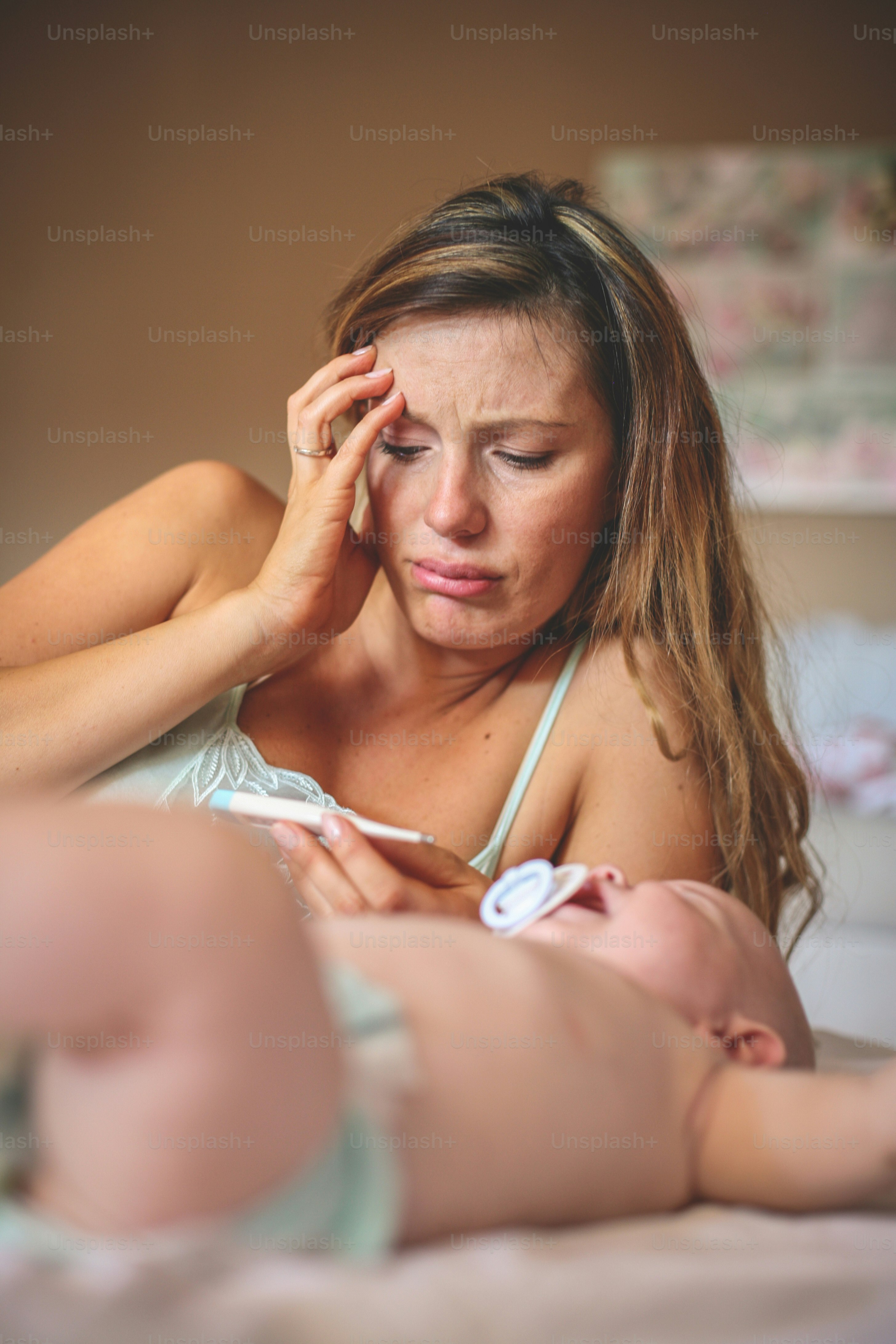Mother with her little baby boy at home.  Worried mother checks his son's temperature.