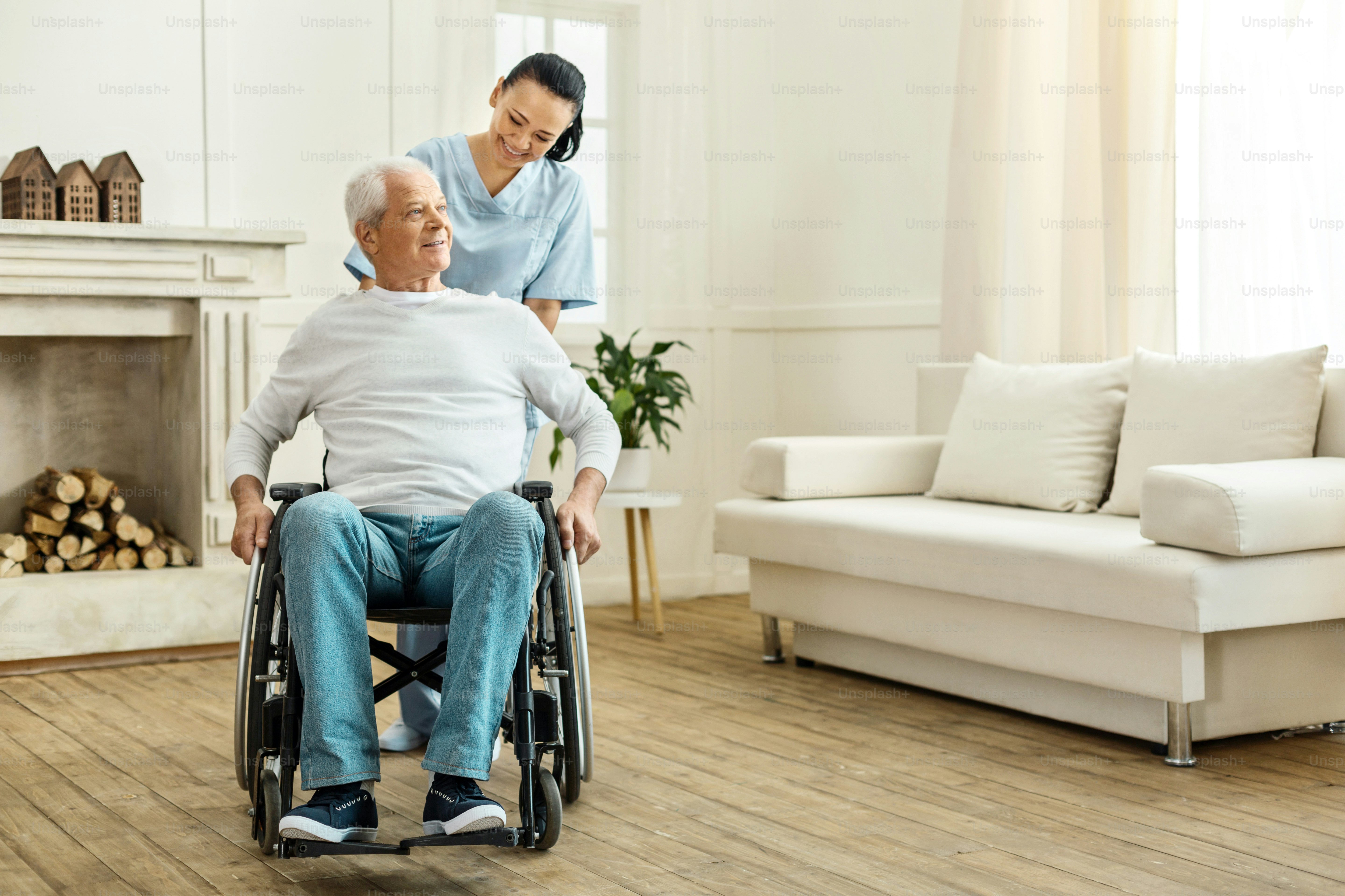 Time for a walk. Cheerful positive female caregiver standing behind her patient and moving a wheelchair while taking him for a walk