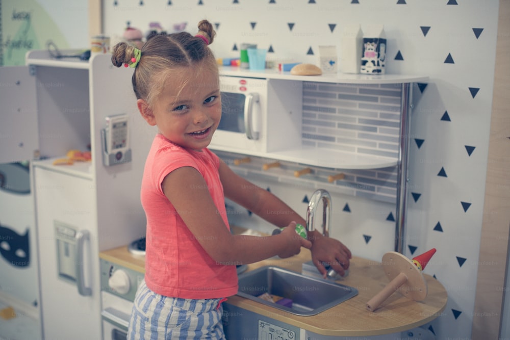 Petite fille dans l’aire de jeux. Fille jouant dans la cuisine des enfants.