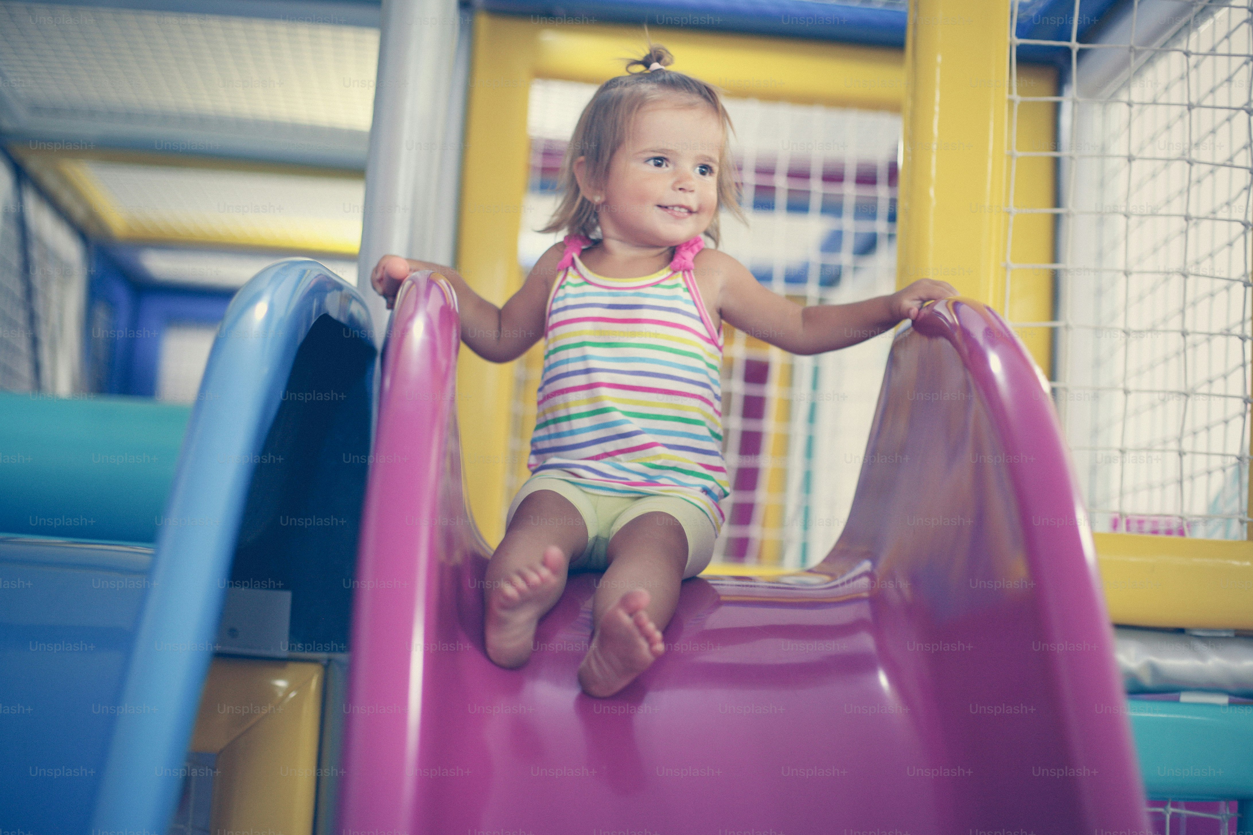 Little girl in playground. Happy little girl sitting on toboggan."n