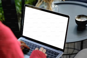 Primer plano de una mujer joven casual usando una computadora portátil en el escritorio. Chica de moda que trabaja desde casa en una computadora portátil