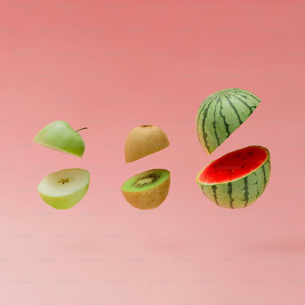 Pastèque, pomme et kiwi tranchés sur fond rose pastel. Concept de fruits minimal.