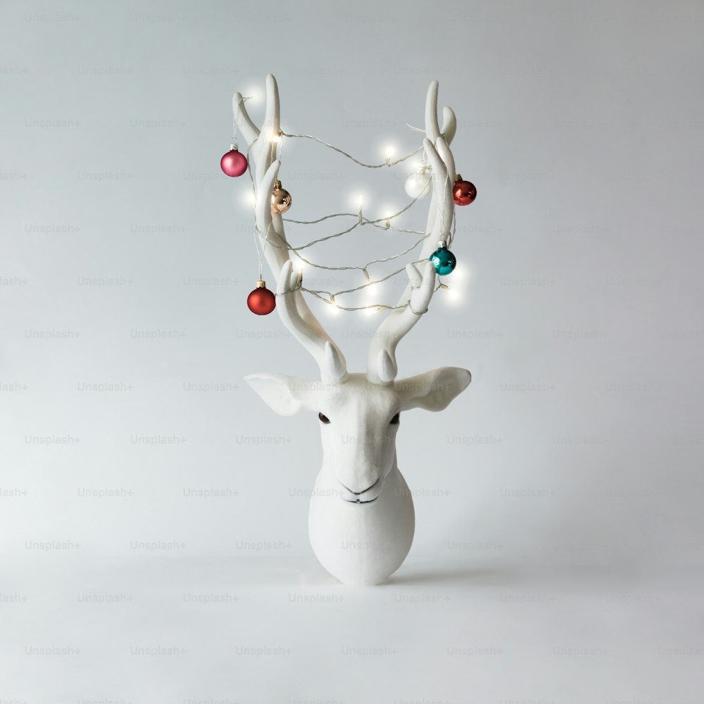 White Christmas reindeer head with antlers with christmas baubles and lights. New Year concept.