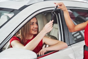 Junge glückliche zwei Frauen in der Nähe des Autos mit Schlüsseln in der Hand - Konzept des Autokaufs.