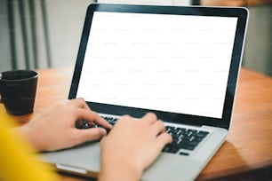 Business Technology Concepts - Digital lifestyle working outside office. Woman hands typing laptop computer with blank screen on table in coffee shop. Blank laptop screen mock up for display of design