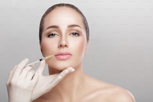Portrait d’une belle femme recevant une injection sur les lèvres. Injections de beauté et cosmétologie