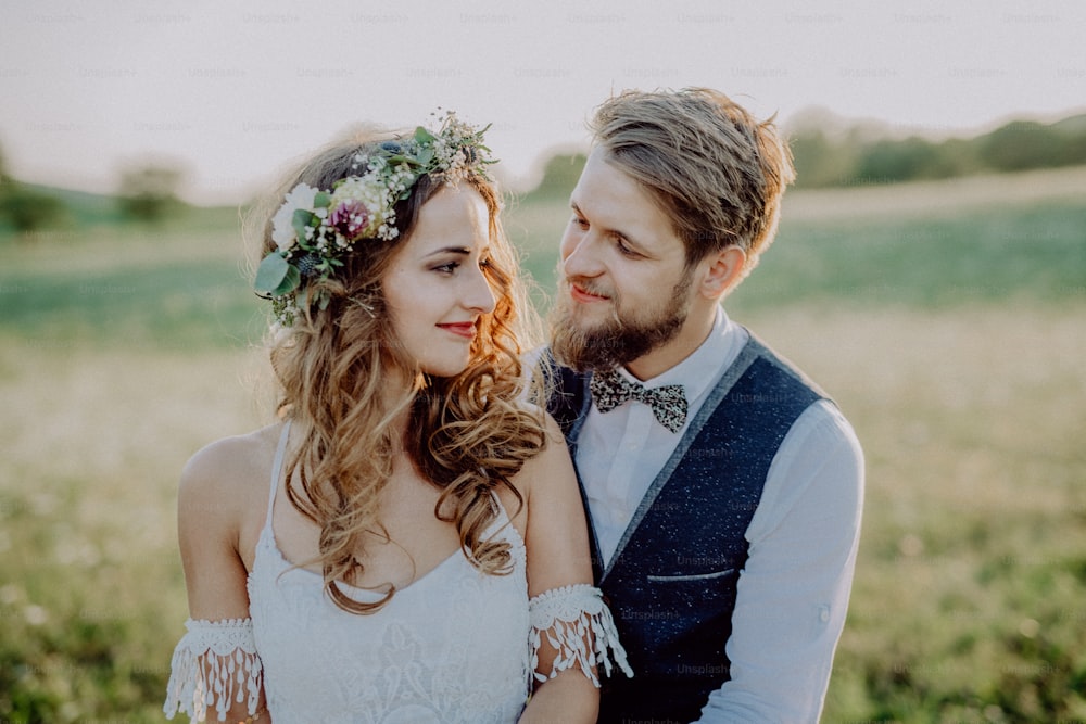 Beautiful young bride and groom outside in green nature at romantic sunset.