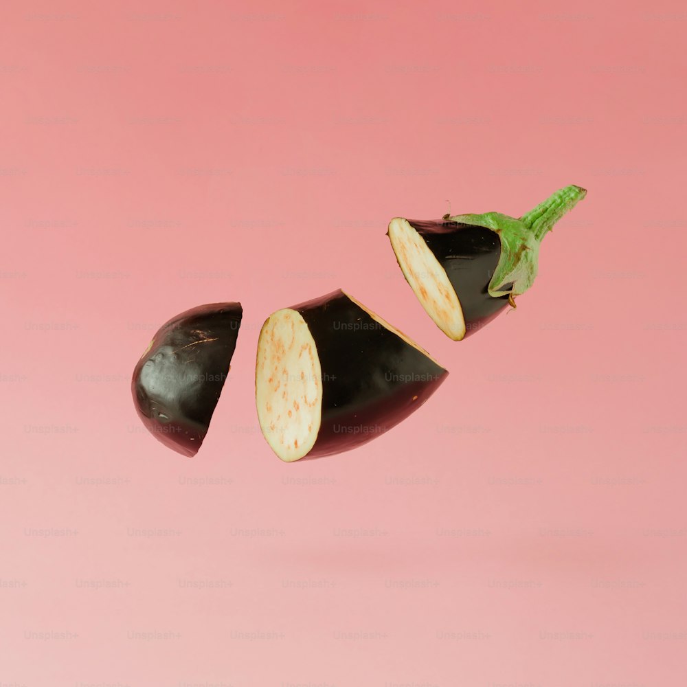 Eggplant sliced on pastel pink background. Minimal fruit concept.