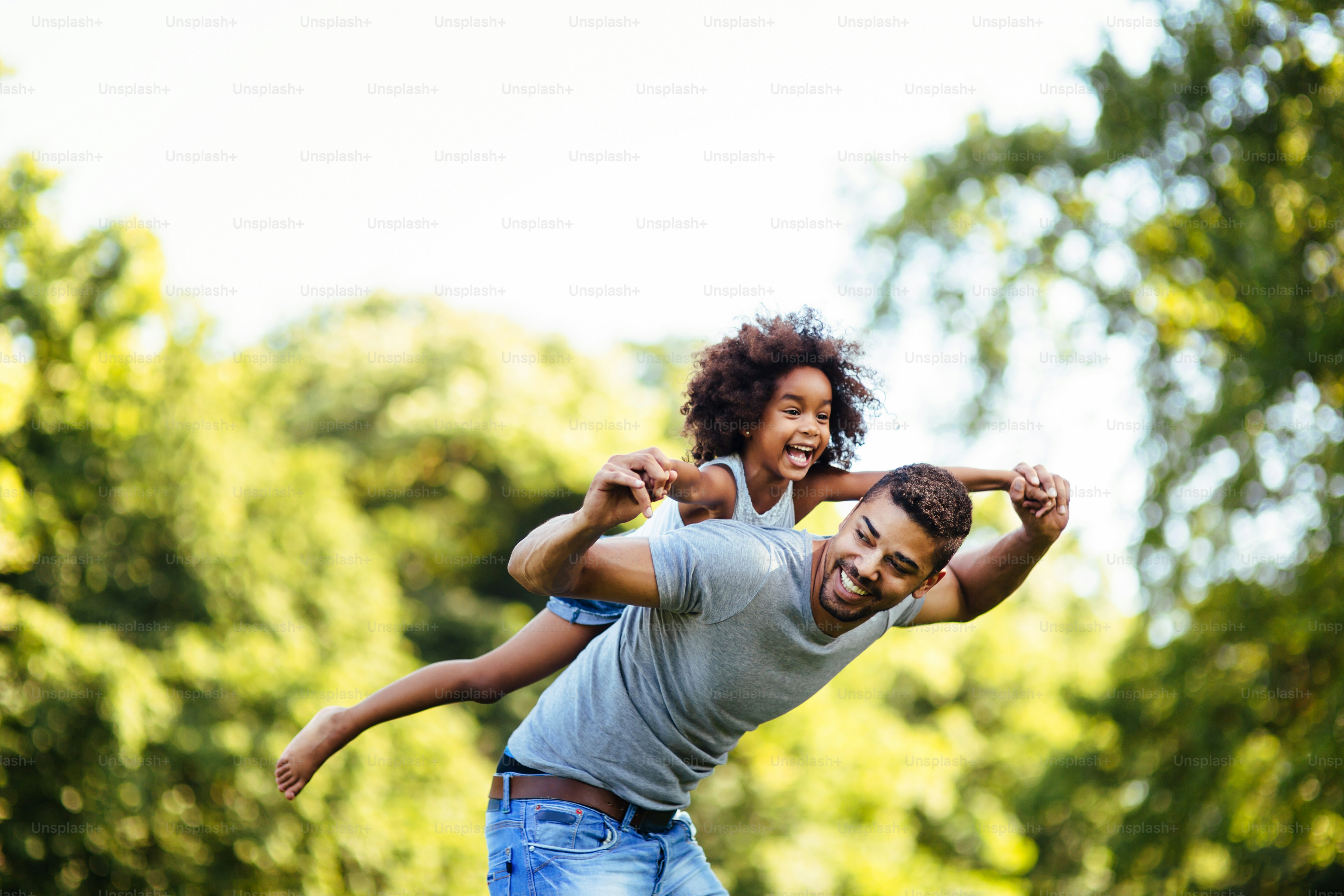 Portrait of young father carrying his daughter on his back in nature