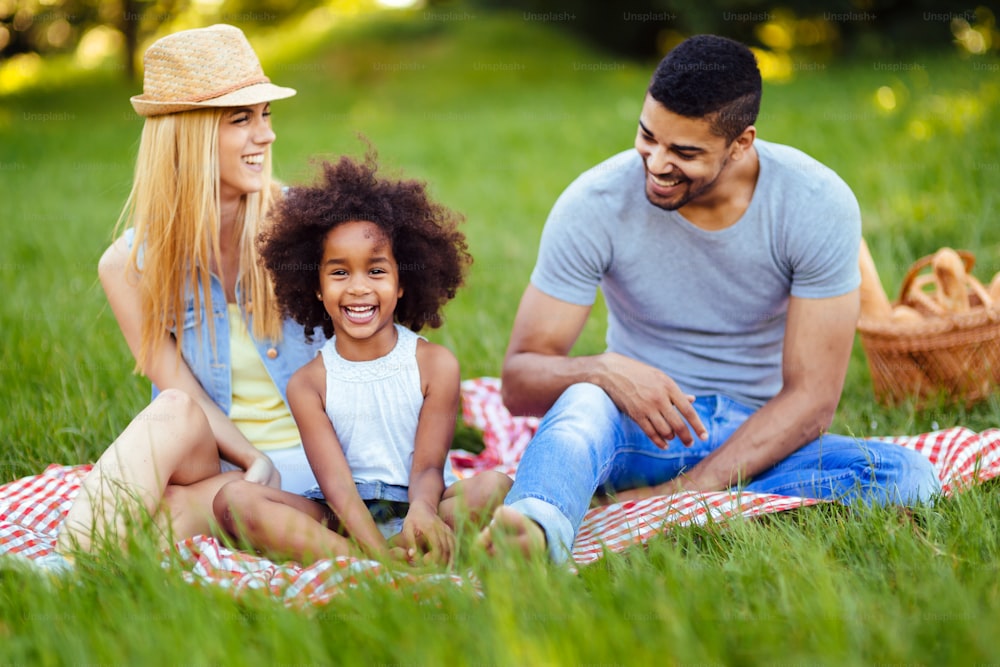 Foto di una bella coppia con la figlia che fa un picnic nella natura
