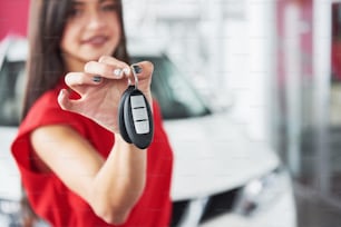 Vendeur de voitures souriant remettant vos nouvelles clés de voiture, votre concession et votre concept de vente. Fille heureuse l’acheteur.