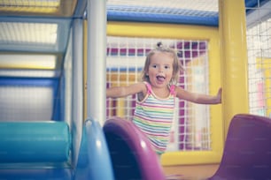 Kleines Mädchen auf dem Spielplatz. Glückliches kleines Mädchen auf dem Schlitten.