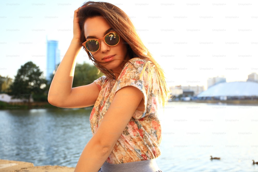 Sommer sonnige Lifestyle-Mode-Porträt der jungen stilvollen Hipster-Frau. Frau mit weißen Zähnen denkt und schaut im Sommer in einem Park seitwärts
