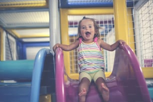 Little girl in playground. Happy little girl sitting on toboggan.