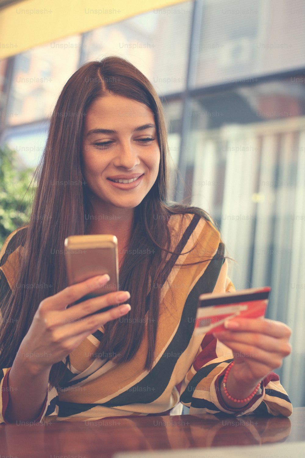 スマートフォンとクレジットカードを使用する若い女性。