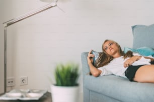 Young beautiful blonde woman lying down on the sofa