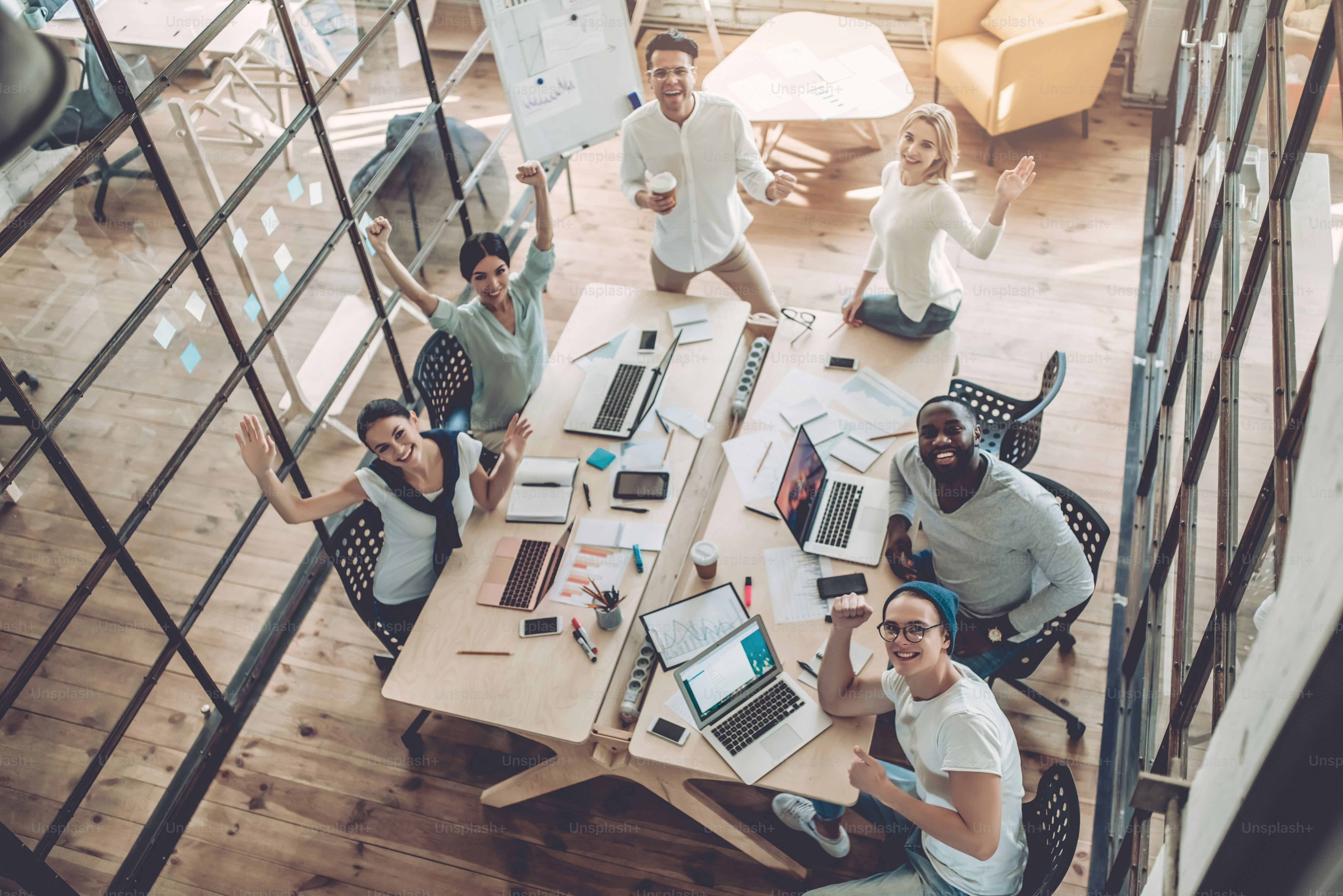 Top view of multiracial young creative people in modern office. Group of young business people are working together with laptop, tablet, smart phone, notebook. Successful hipster team in coworking. Freelancers.
