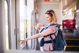 Junge Mutter, die mit einem kleinen Jungen mit dem Zug reist. Bahnreise einer schönen Frau und ihres Sohnes.
