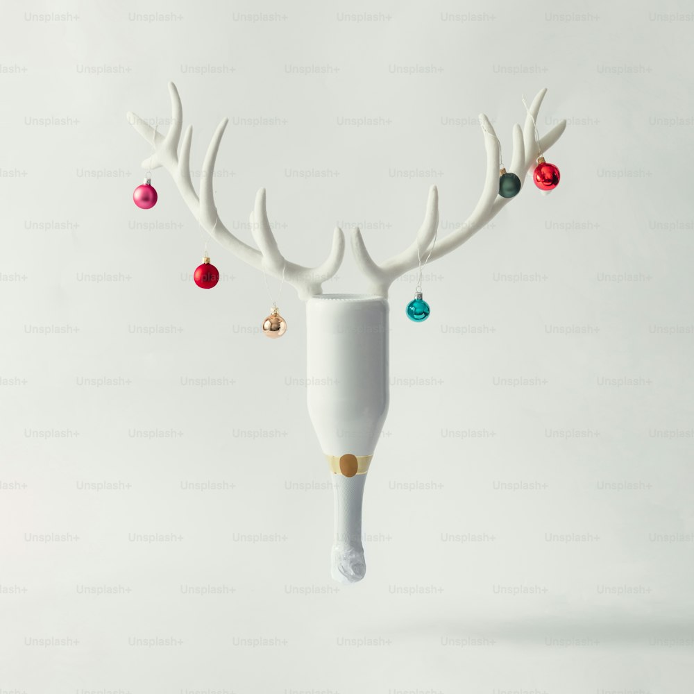 White champagne bottle with reindeer antlers and Christmas baubles. New year party concept.