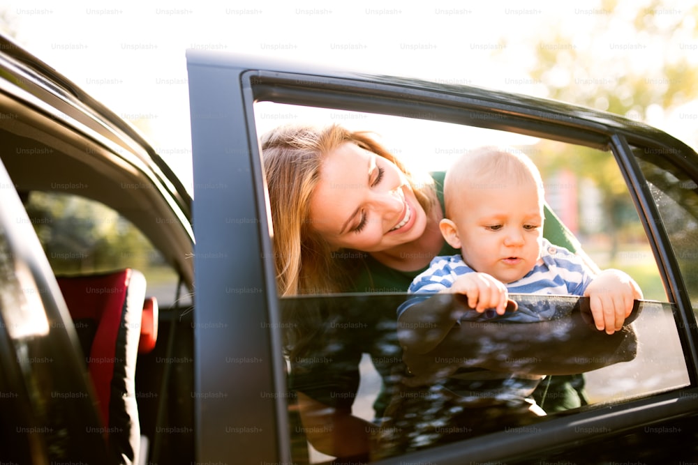 어린 아들을 팔에 안고 있는 젊은 어머니. 차 옆에 서 있는 아들과 함께 있는 여자.