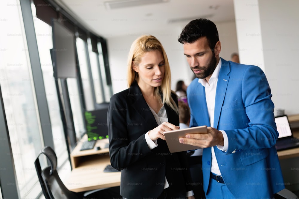 Young attractive business couple using tablet in their company