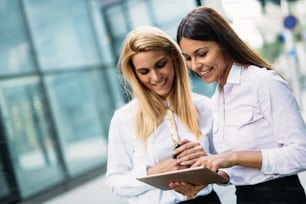 Picture of two young beautiful women as business partners standing outside