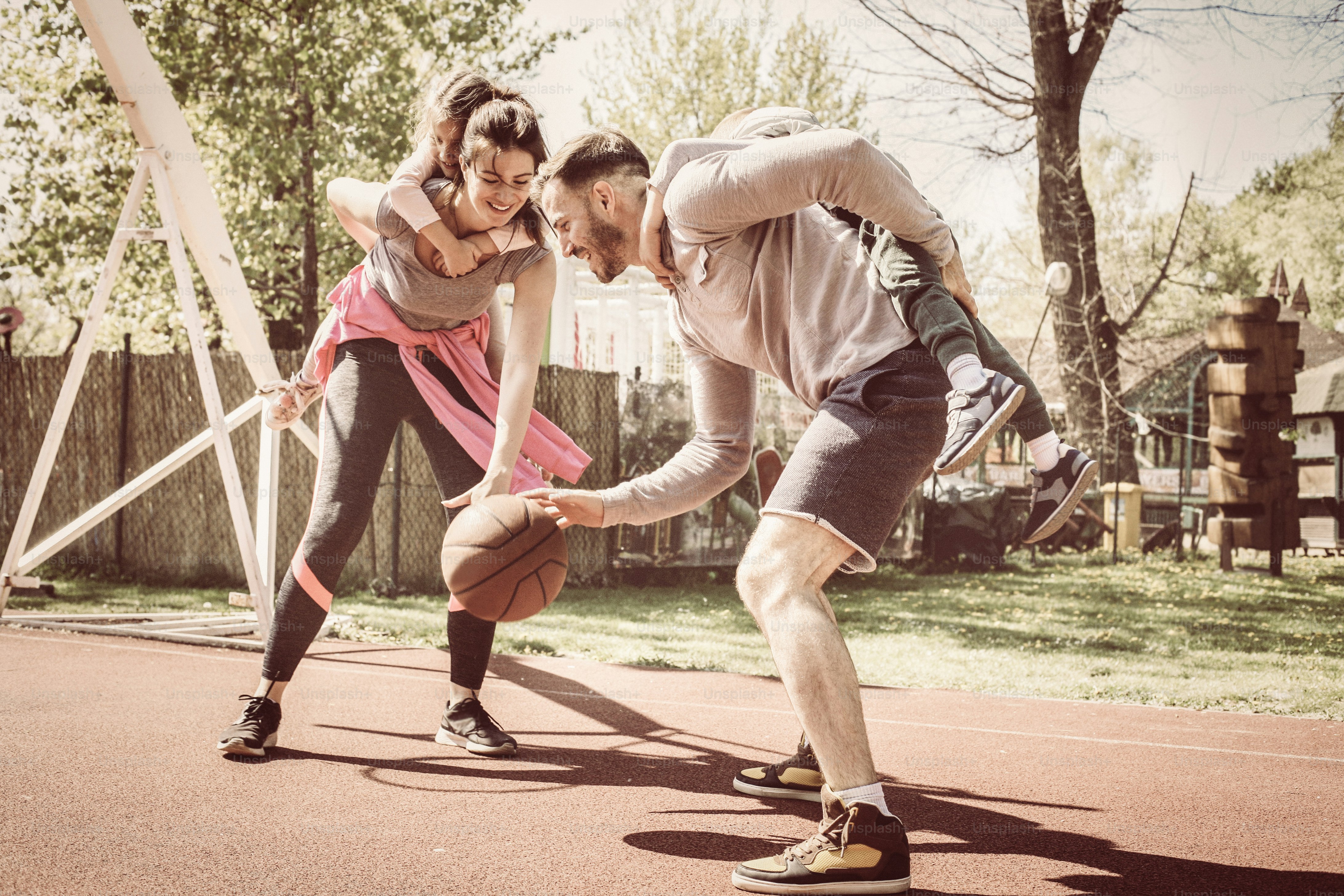 Parents carrying children on piggyback and playing basketball.
