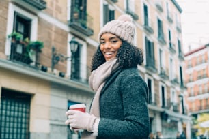 겨울에 마드리드 거리를 배회하는 커피를 마시는 젊은 흑인 여성