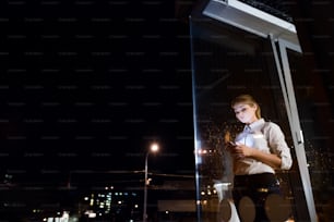 Bela jovem empresária com tablet no escritório trabalhando tarde da noite. Tiro através do vidro.