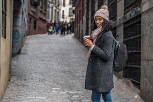 Young black woman drinking coffee wandering in the streets of Madrid on winter