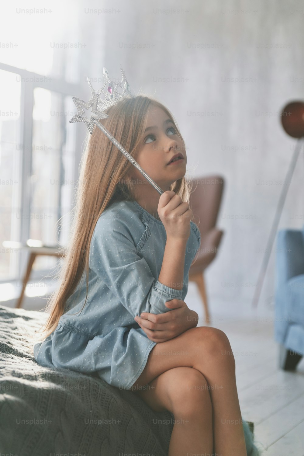 Süßes kleines Mädchen, das mit einem Zauberstab spielt, während es Zeit zu Hause verbringt