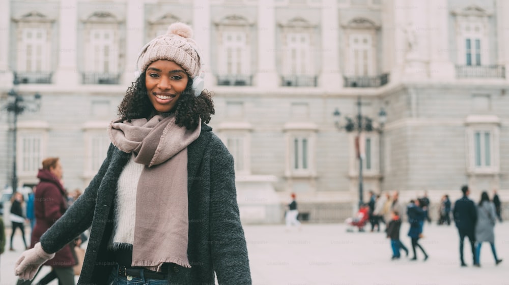 Joven negra escuchando música y bailando en el teléfono móvil cerca del palacio real en invierno "n