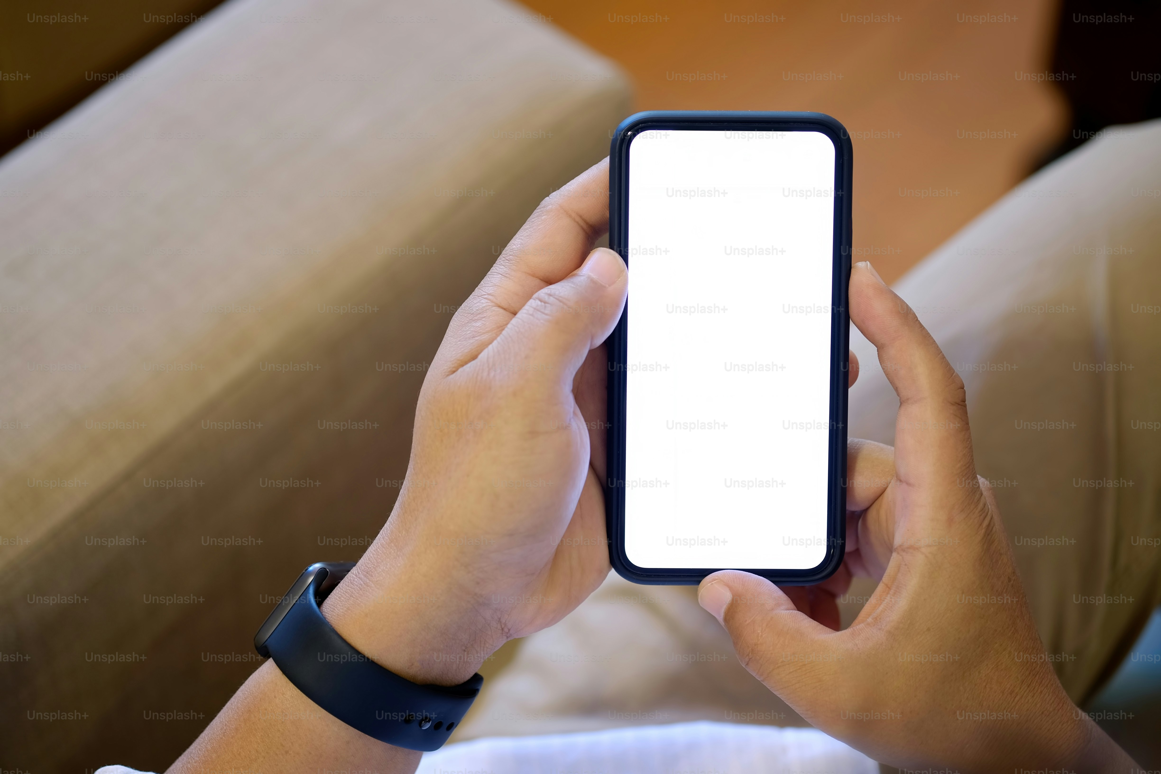 Closeup shot of an unidentifiable man using a smartphone at living room background.