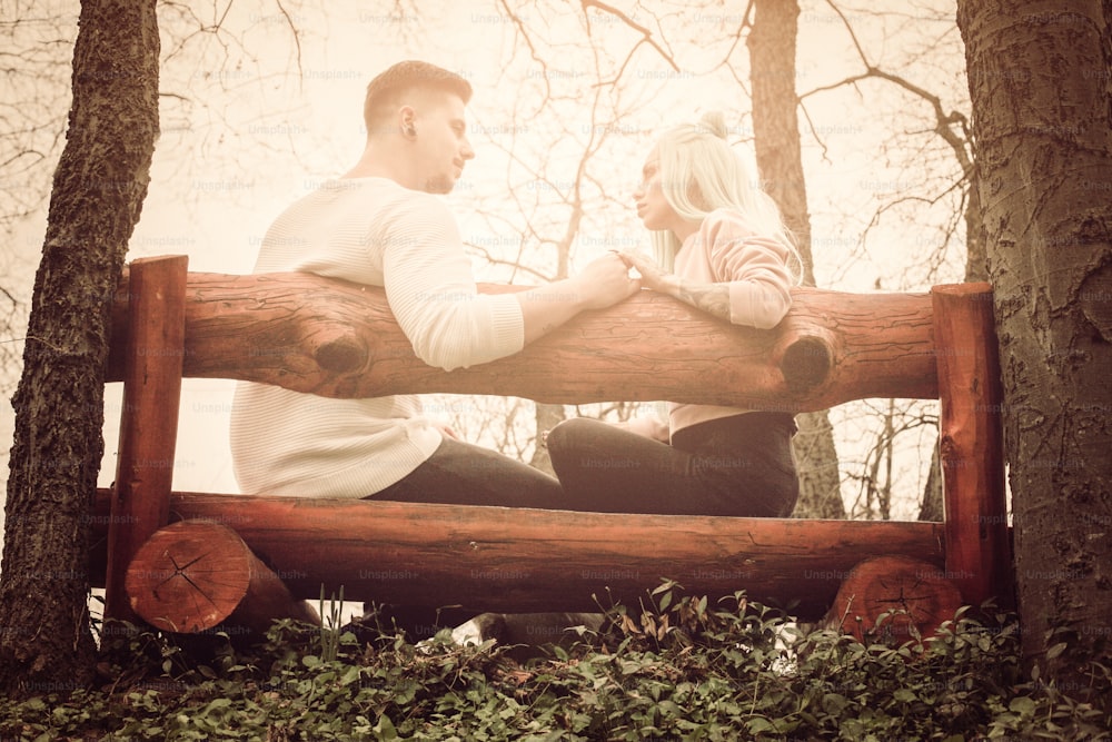 Couple  holding hands looking each other. and sitting on bench.