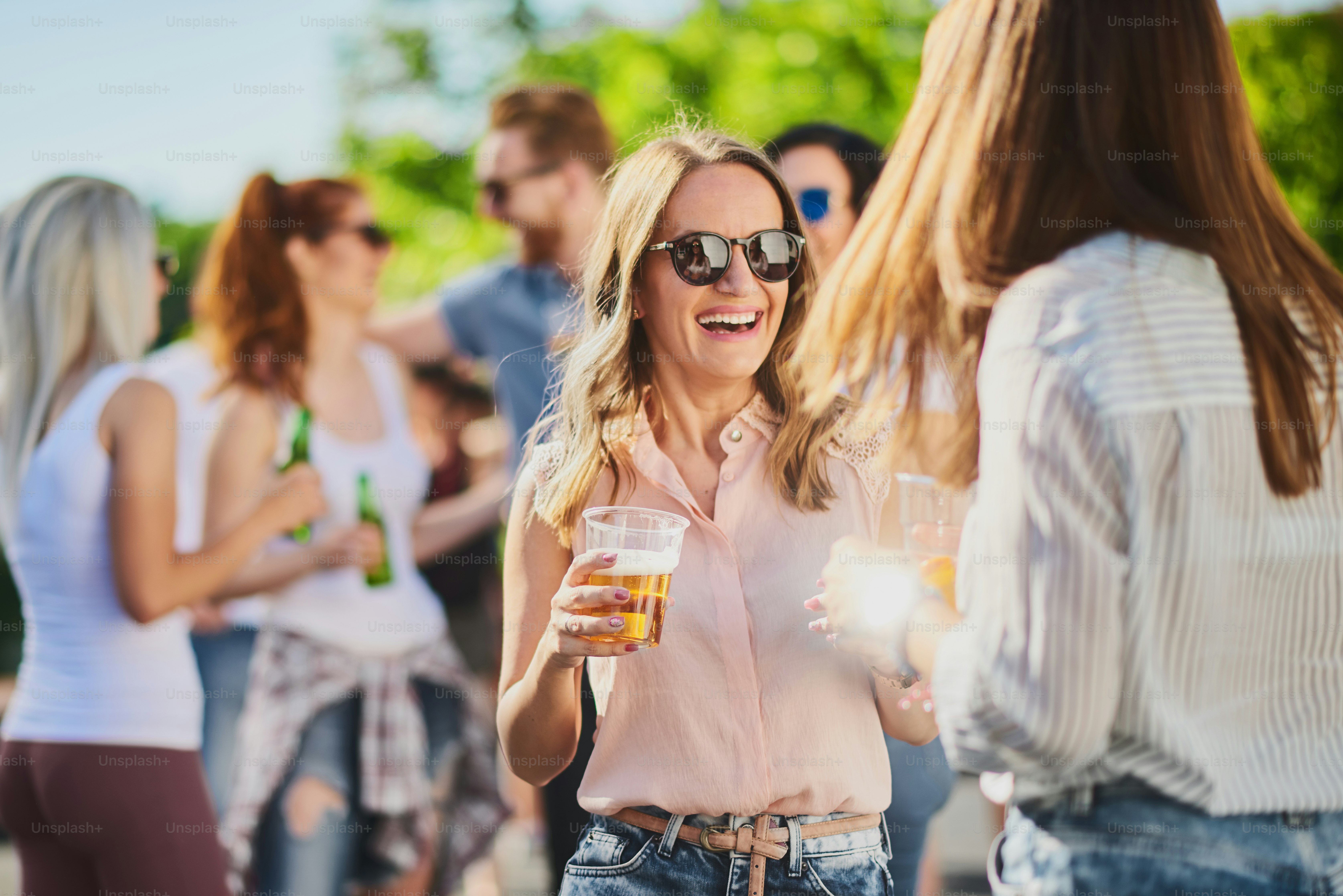 Group of people standing, drinking an having a good time at outdoor party