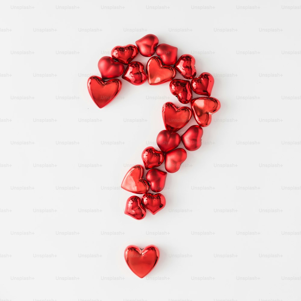 Question mark made of red hearts on bright background. Flat lay. Minimal love concept.