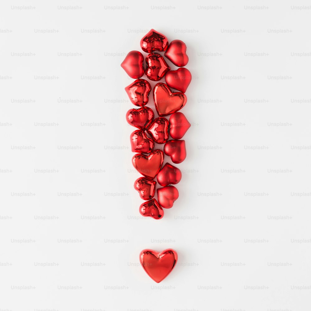 Signo de exclamación hecho de corazones rojos. Plano tendido. Concepto de amor minimalista.