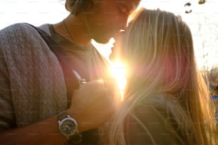 Un couple heureux et souriant amoureux s’étreint et s’embrasse dans le parc d’attractions. Soirée ensoleillée et chaude du printemps