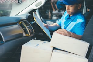 Young Delivery Man Checking Customer List On Clipboard.