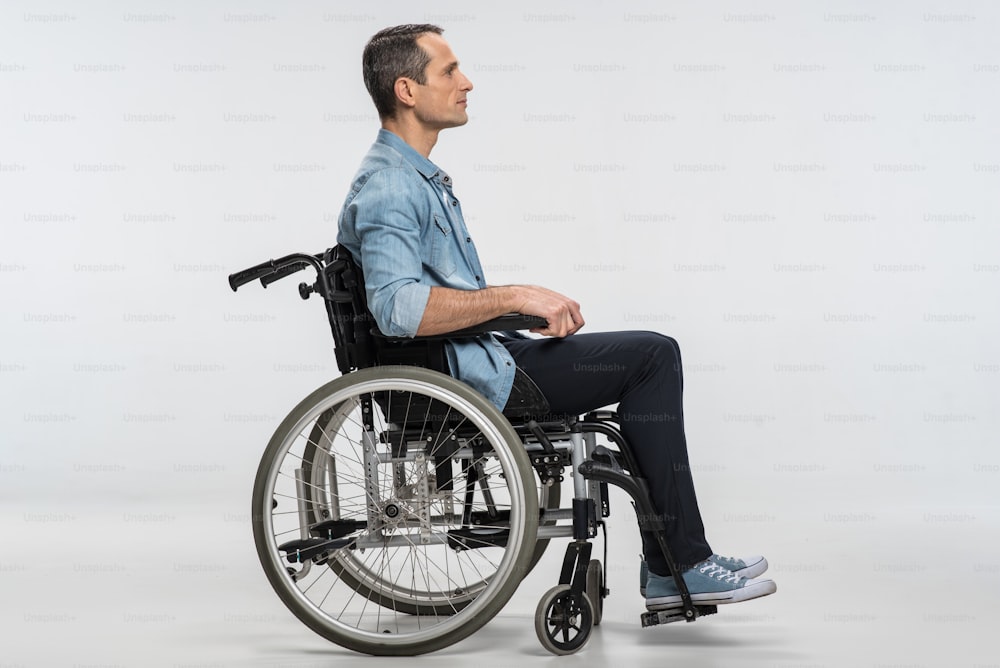 Nessun limite.  Uomo disabile piacevole fiducioso, colpo di profilo dell'uomo in sedia a rotelle