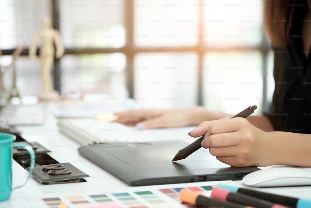 Femme de conception graphique créative travaillant sur une table avec un stylo souris et un PC de bureau.
