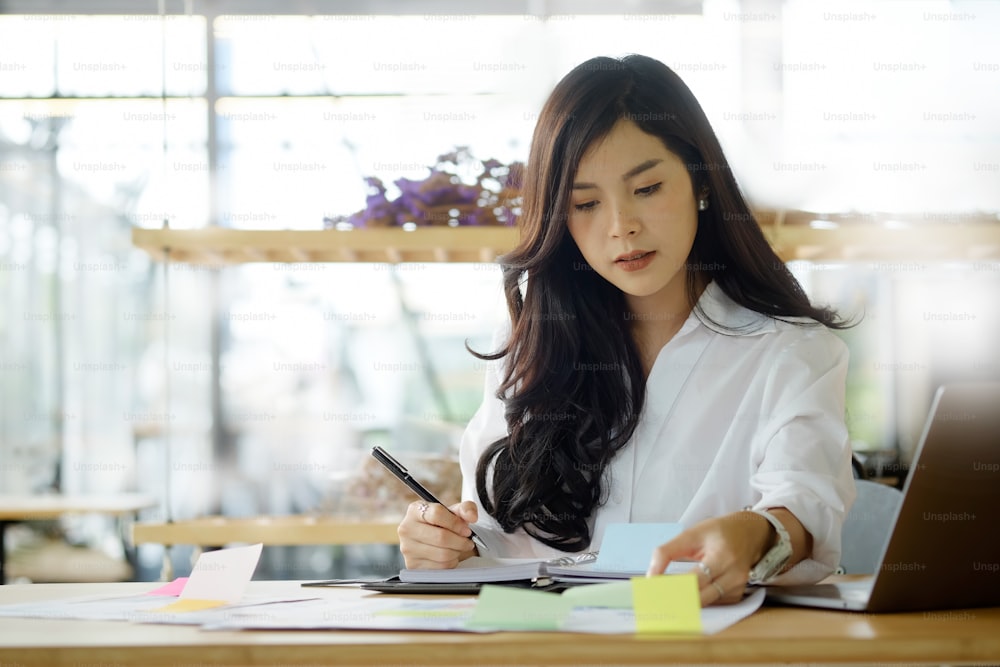 Cropped shot of an attractive young businesswoman working on document and laptop in her office.