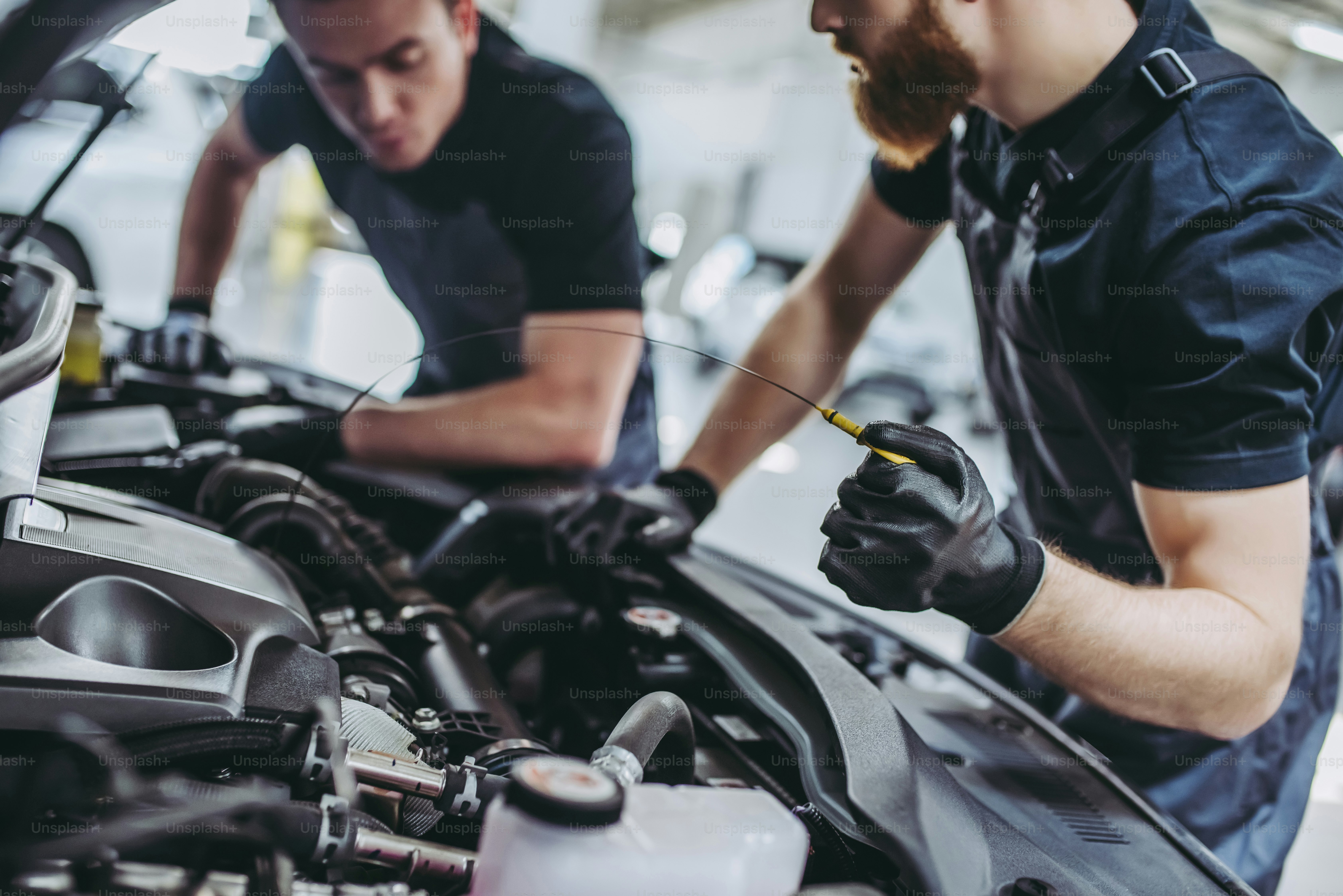 Cropped image of two handsome mechanics in uniform are working in auto ...