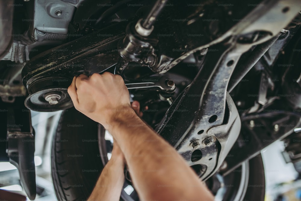 Image recadrée d’un beau mécanicien en uniforme travaillant dans l’entretien automobile. Réparation et entretien automobile.