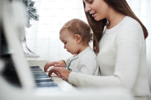하얀 피아노를 연주하는 어머니와 딸, Wiew를 닫습니다.