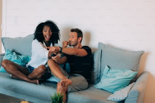 Happy young couple relaxed at home in the couch having fun watching tv