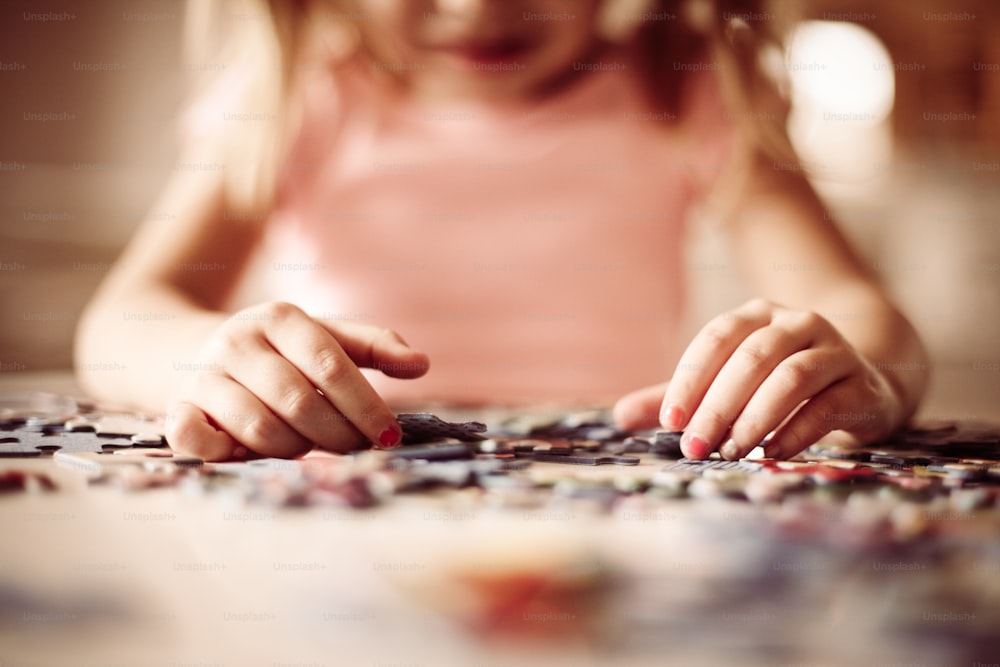 Girl playing puzzle. Focus on girl hands.