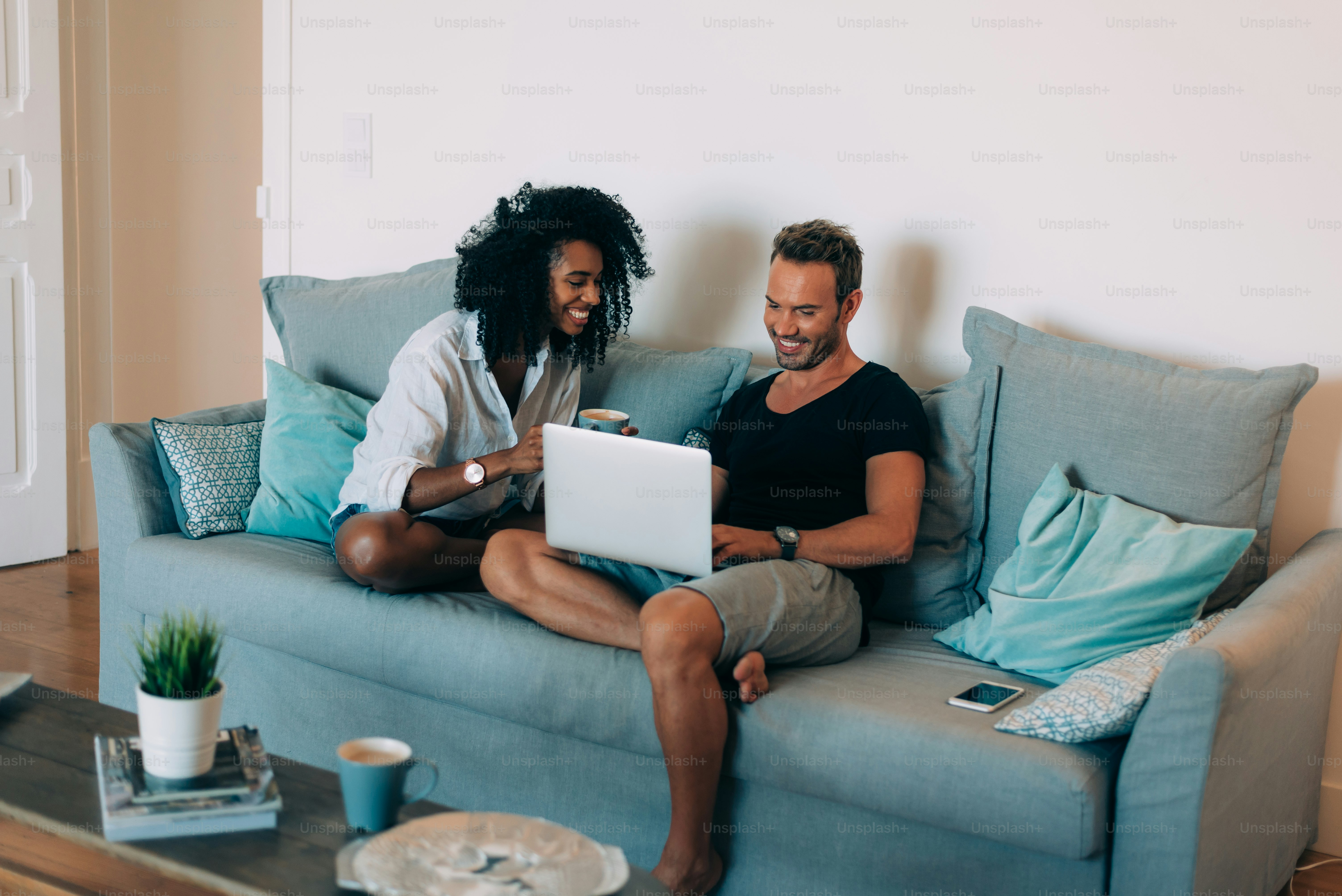 Happy young couple relaxed at home in the couch on the mobile phone and computer